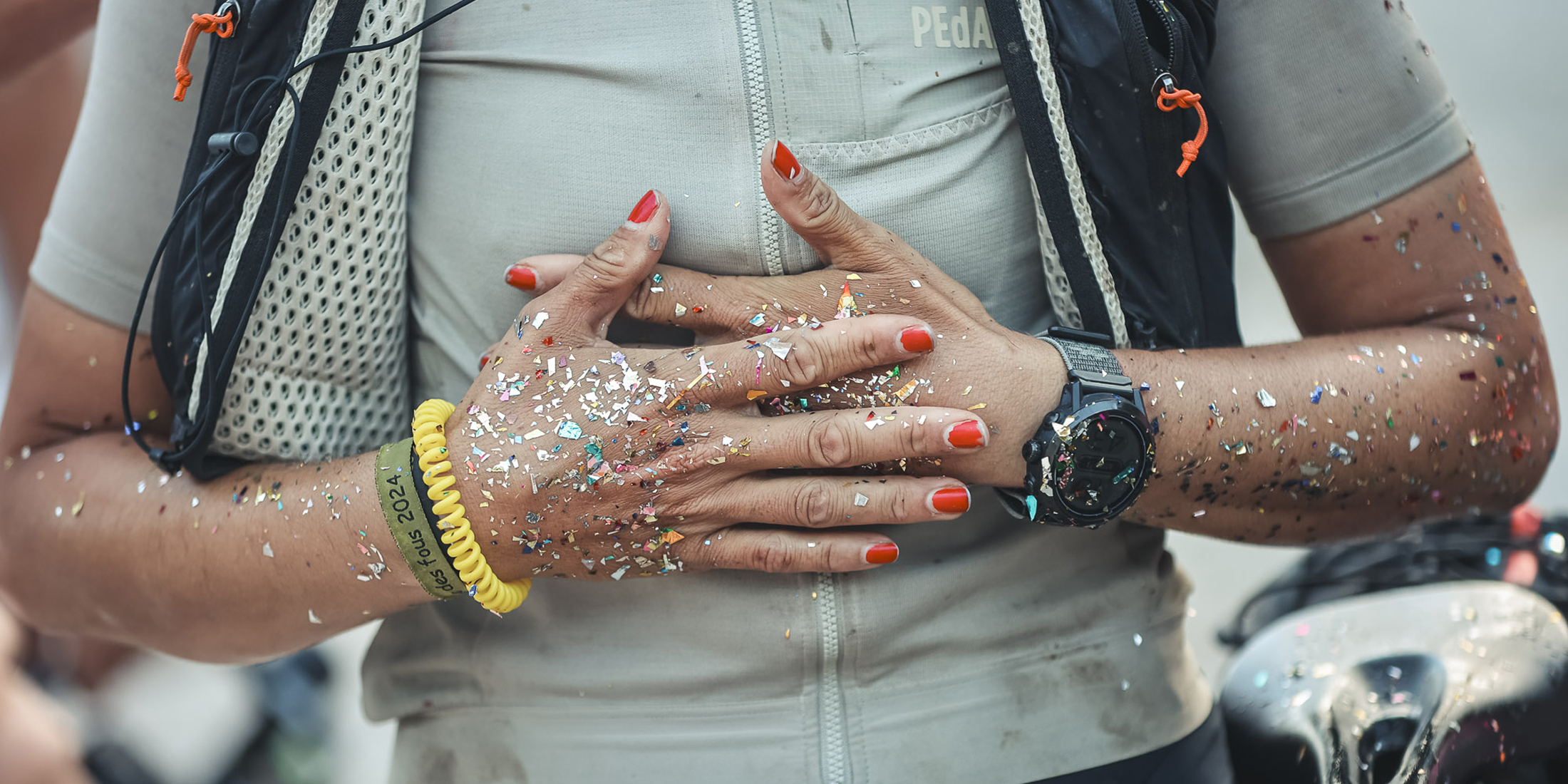 Gloworm athlete Dilara Tuna celebrating at the finish of the 2026 Trans Balkan Race, covered in glitter.